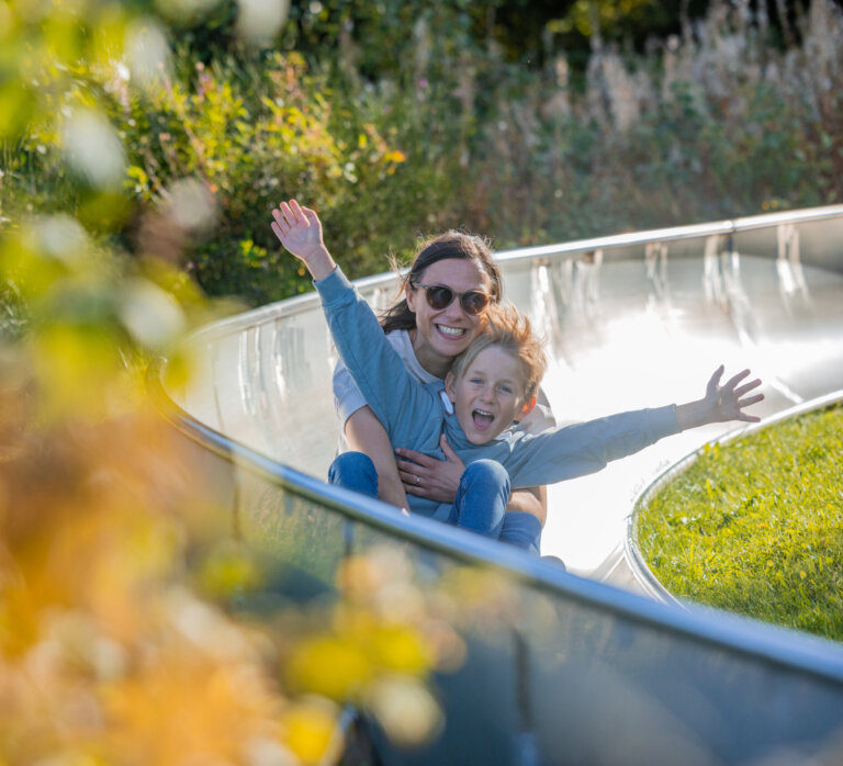 Sommerrodelbahn Winterberg mit Kind und Begleitperson auf einer kurvigen Bahn am Erlebnisberg Kappe.
