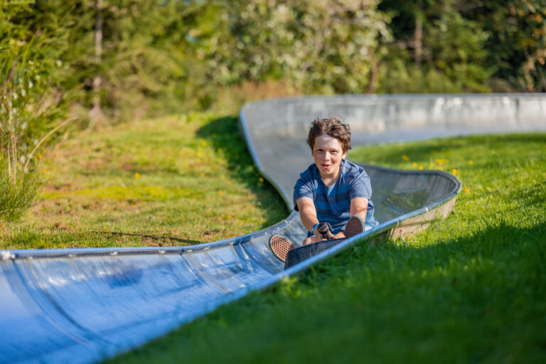 Sommerrodelbahn Winterberg mit Jugendlichem auf der kurvenreichen Rodelstrecke und Freizeitspaß im Sauerland.